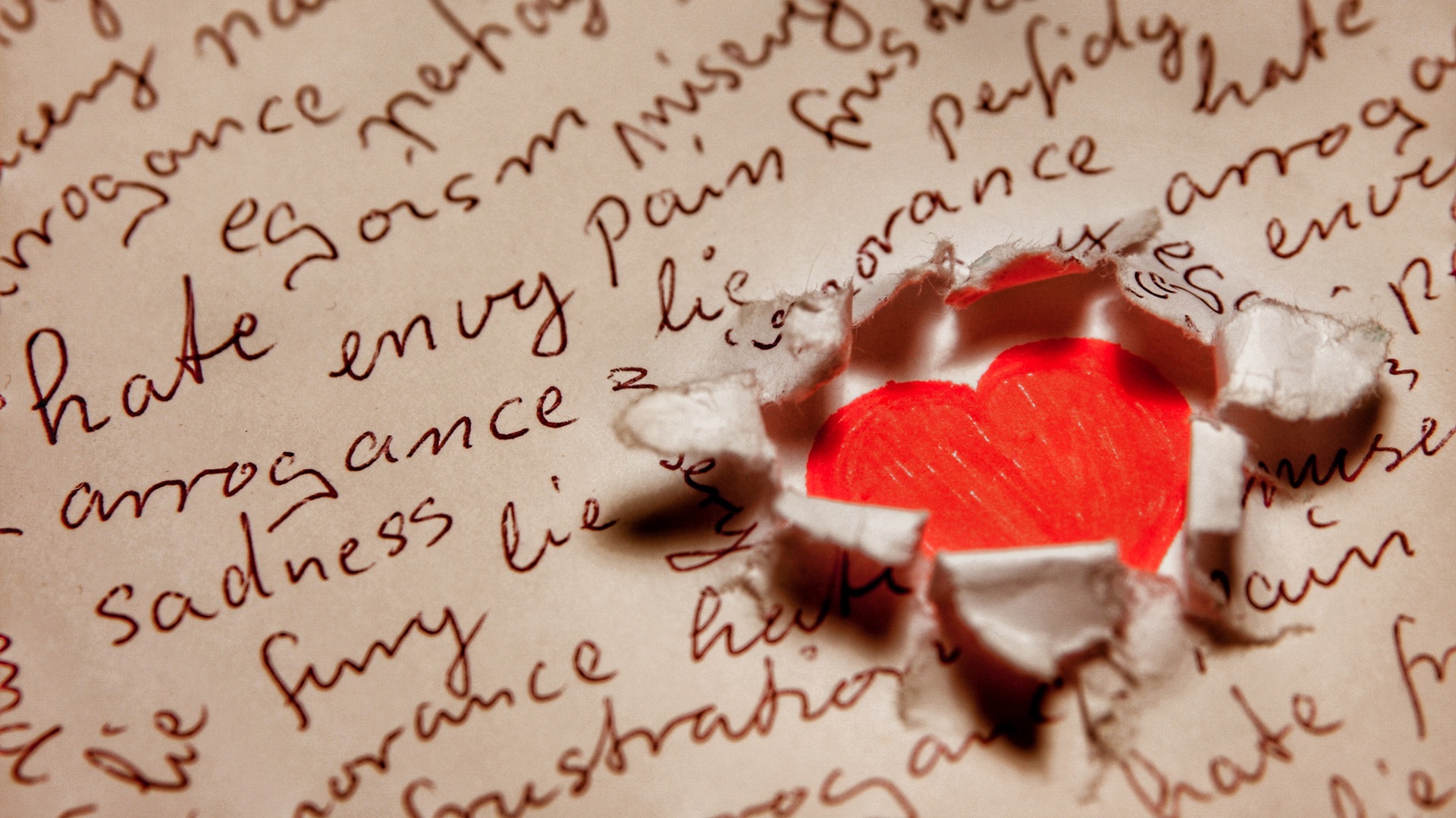 Roztrhaný papír s negativními slovy, pod nímž prosvítá červené srdce. Symbolizuje lítost a skrytou naději.