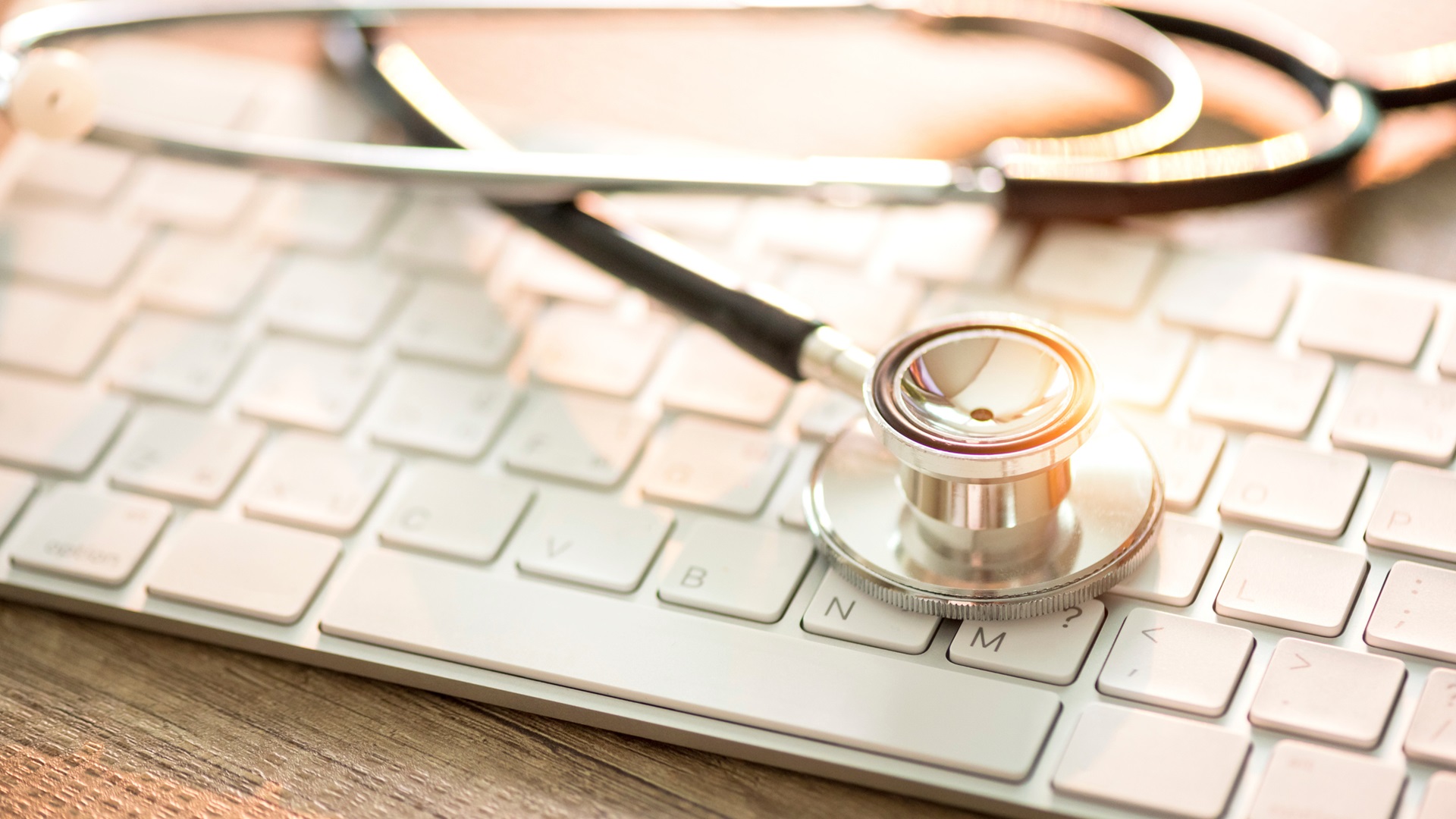 Stetoskop ležící na klávesnici počítače. Symbolizuje spojení medicíny a moderních technologií v péči.