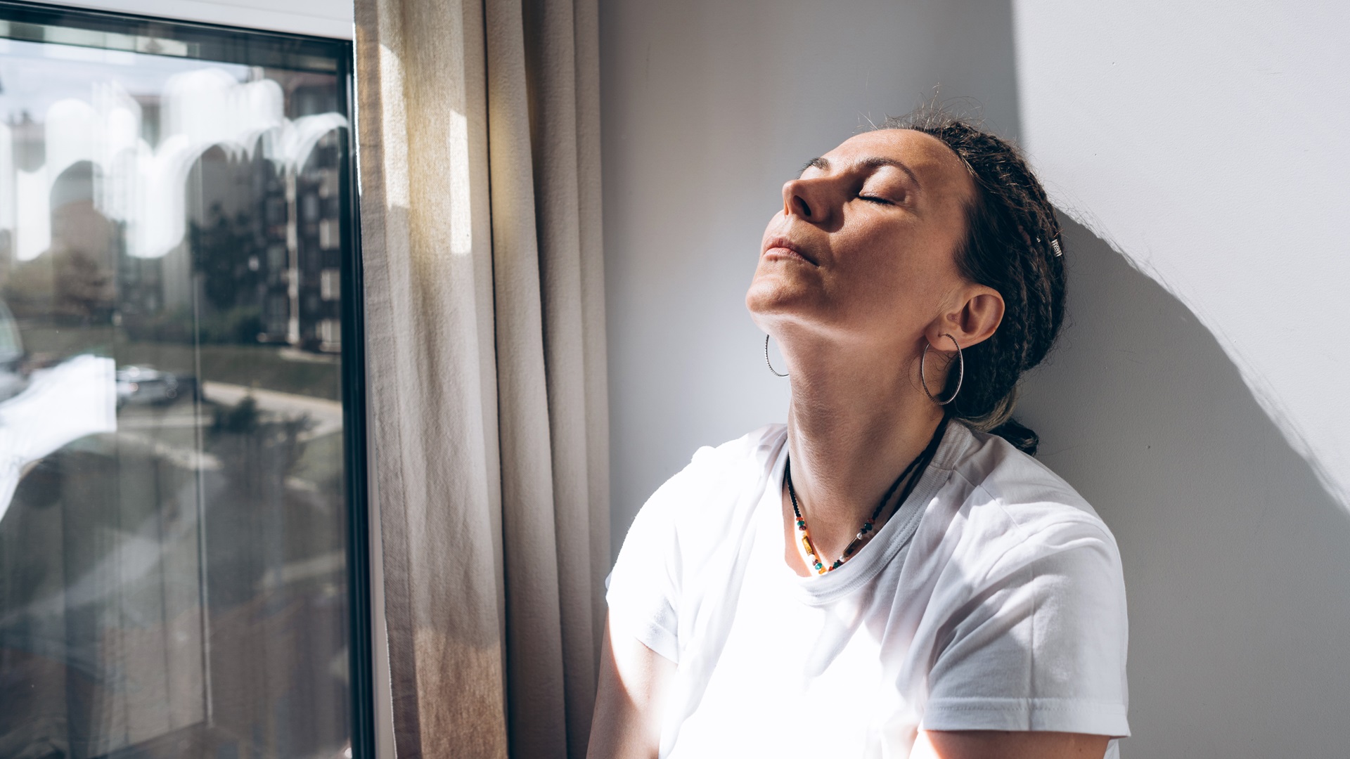 Žena se zavřenýma očima a hlavou zakloněnou k oknu, užívající si slunce. Symbolizuje duševní pohodu a odpočinek.