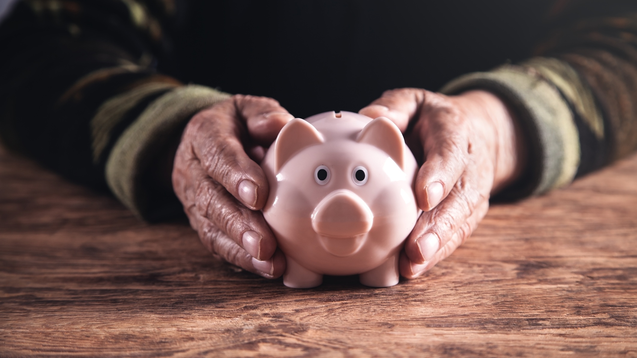 Ruce držící prasátko na ukládání peněz